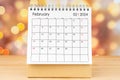 February 2024 desk calendar on wooden table with gold light bokeh background Royalty Free Stock Photo