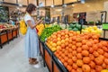 Woman customer wearing face mask, shopping and picking lime and lemon fruits in supermarket grocery