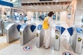 Woman wearing a protective medical mask applies a transport card to pass through a turnstile at the