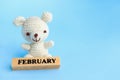 February text on wood block and teddy bear crochet knitting on light blue background. Royalty Free Stock Photo