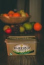 Dairymaid premium butter container on top of a wooden table with healthy fruit in the background