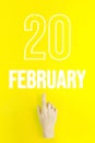 February 20th. Day 20 of month, Calendar date.Hand finger pointing at a calendar date on yellow background.Winter month, day of