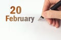 February 20th. Day 20 of month, Calendar date. The hand holds a black pen and writes the calendar date. Winter month, day of the