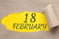 february 18. 18th day of the month, calendar date.Hole in paper with edges torn off. Yellow background is visible