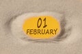 February 1. 1th day of the month, calendar date. Hole in sand. Yellow background is visible through hole