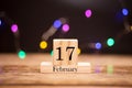 February 17th. Day 17 of february month set on wooden calendar at center of dark background with garland bokeh. Royalty Free Stock Photo