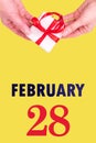 February 28th. Festive Vertical Calendar With Hands Holding White Gift Box With Red Ribbon And Calendar Date