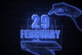 February 29th. A hand holding a phone with a calendar date on a futuristic neon blue background. Day 29 of month.