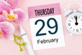 February 29th mini calendar for February 2024 and pink orchid with alarm clock background