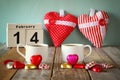 February 14th wooden vintage calendar with colorful heart shape chocolates next to couple cups on wooden table. selective focus Royalty Free Stock Photo