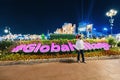 Tourist visitor takes a photo against the background of the glowing inscription Global Village