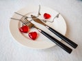 February 14 is Valentine`s Day, a holiday for all lovers. Still life of a white plate, knife, fork, three red hearts, two togethe