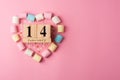 February 14 wooden calendar in a heart frame made of pink, blue, yellow and white marshmallows and hearts on a pink background. Royalty Free Stock Photo