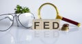 FED concept on wooden cubes and flower glasses coins and magnifier on the white background