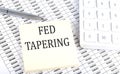 FED TAPERING - business concept, message on sticker on chart background