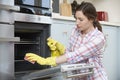 Fed Up Woman Cleaning Oven At Home