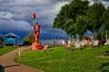 Red fairway buoy, colorful sunchairs and green tree against dark grey sky in Fedderwardersiel, Germany