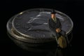 Miniature man seating on Half Dollar coin Black background Macro Royalty Free Stock Photo