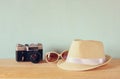Fedora hat, sunglasses old vintage camera over wooden table. relaxation or vacation concept