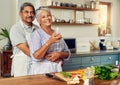 Feed the body, nourish the heart. Portrait of a happy mature couple drinking wine while cooking a meal together at home. Royalty Free Stock Photo