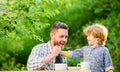 Feed son solids. Feed your baby. Natural nutrition concept. Dad and cute toddler boy having lunch outdoors. Child care