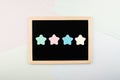 Feedback, vote, Rating, review concept. Four pastel Star Shapes on blackboard nameplate on light