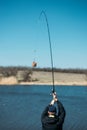 Feeder fishing. Carp Fishing Steel Basket Bait Feeder on rod close up. Male fisherman fishing at sun day on the lake