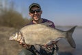 Feeder fishing. Fisherman with big bream fish in hands at wild river Royalty Free Stock Photo