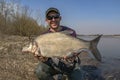 Feeder fishing. Fisherman with big bream fish in hands at wild river