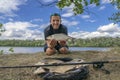 Feeder fishing. Fisherman with vimba bream fish in hands and tackle at wild river shore