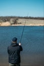 Feeder fishing. Male fisherman fishing at sun day on the lake. Man in jacket catches bream fish in early spring. Fishing hobby