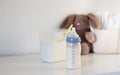 A feeding bottle with baby formula milk on white table, dry powder milk in a can in background Royalty Free Stock Photo