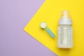 Feeding bottle with infant formula and powder on color background, flat lay. Space for text Royalty Free Stock Photo