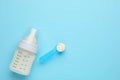 Feeding bottle with infant formula and powder on light blue background, flat lay. Space for text Royalty Free Stock Photo