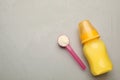 Feeding bottle with infant formula, scoop of powder and space for text on grey table, flat lay. Baby milk Royalty Free Stock Photo