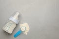 Feeding bottle with infant formula, scoop of powder and space for text on grey table, flat lay. Baby milk Royalty Free Stock Photo