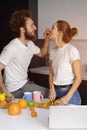 Feeding orange to girl young man embracing each other enjoying their their morning coffee in a new house. Making fun at Royalty Free Stock Photo