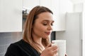 Feel good with coffee. Close up of young curvy woman closing her eyes while drinking tea or coffee in the kitchen Royalty Free Stock Photo