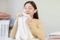 Feel softness, smiling asian young woman, girl touching fluffy towel cotton, smelling fresh clean clothes on table after washing, Royalty Free Stock Photo