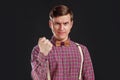 Feeling so angry! Angry young man in vintage shirt and bow tie with hairstyle looking at camera and making a face and show a fist