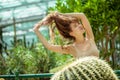 Pretty young woman standing near the cactus and holding her hair Royalty Free Stock Photo