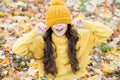 Feeling comfortable. childhood happiness. beauty of fall nature. happy kid wear sweater and hat. teen girl among fallen Royalty Free Stock Photo