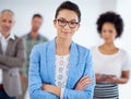 Feeling confident and comfortable. Confident young businesswoman smiling at the camera with coworkers in the background. Royalty Free Stock Photo