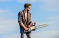 Feeling confident. Risky temper. Powerful chainsaw. Sharp blade. Handsome man with chainsaw blue sky background