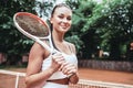 Feeling confident of winning. Beautiful young woman holding tennis racket and looking happy Royalty Free Stock Photo