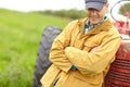 Feeling content. a smiling farmer standing next to his tractor with his arms crossed and looking down. Royalty Free Stock Photo