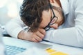 Feeling down in the dumps after a stressful work day. a young businessman with his head down on an office desk.