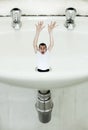 Feeling drained. A young man being sucked down the drain in a giant basin. Royalty Free Stock Photo