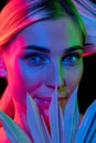 High fashion model in colorful bright neon lights posing at studio. Portrait of beautiful woman with trendy glowing make Royalty Free Stock Photo