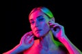 High fashion model in colorful bright neon lights posing at studio. Portrait of beautiful woman with trendy glowing make Royalty Free Stock Photo